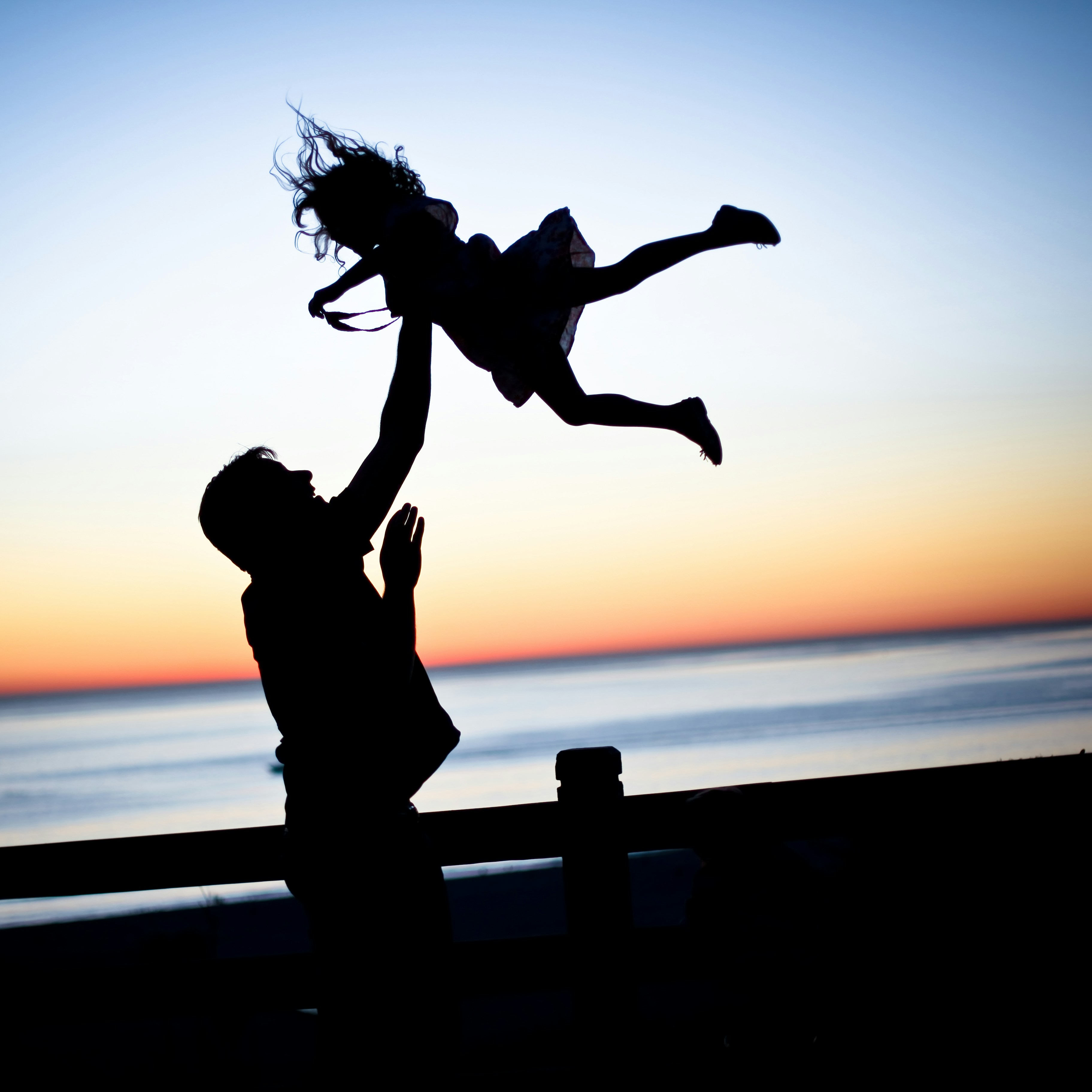 Parent and child silhouetted at sunset